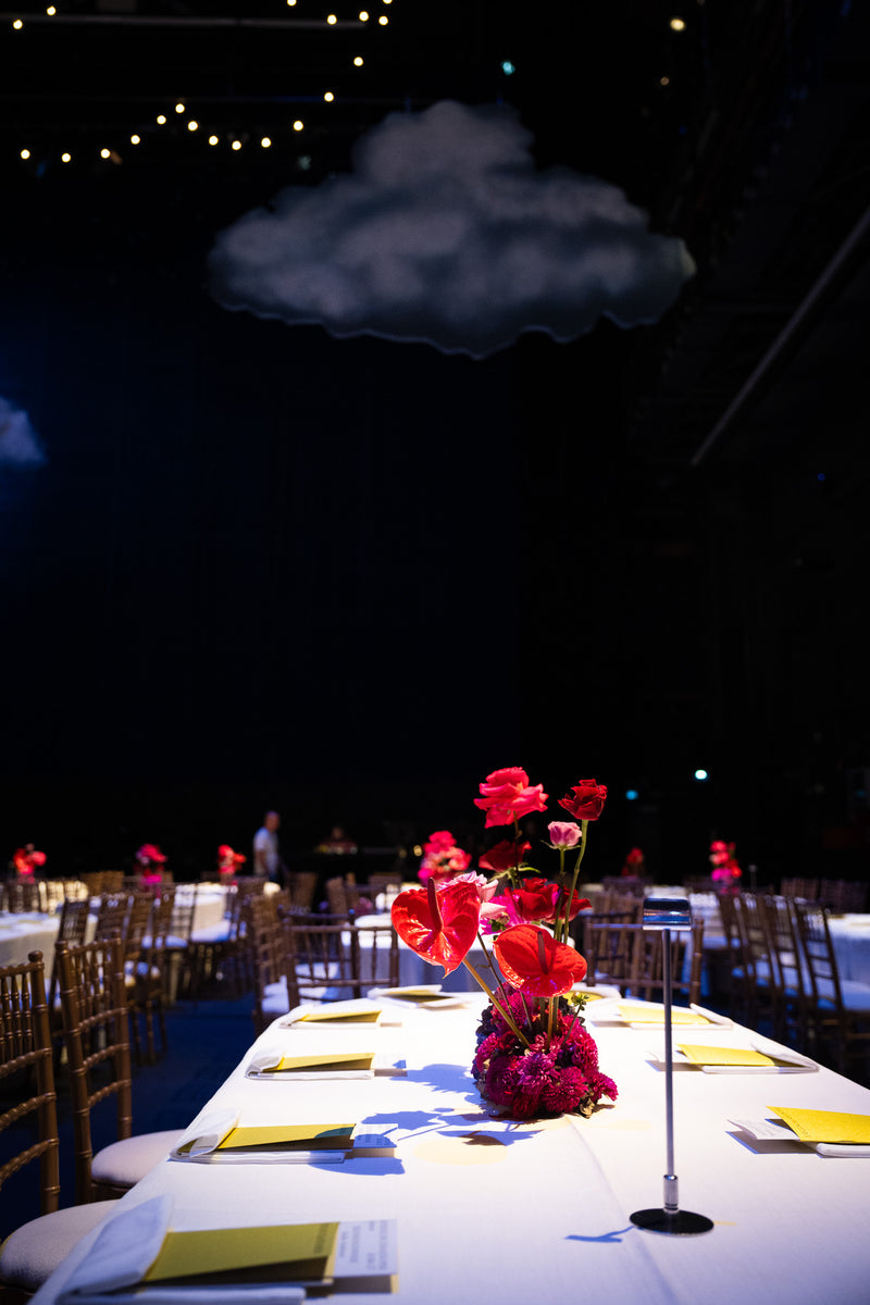 Florale Tischdekoration von Blumen Bahlmann in der Bayerischen Staatsoper, mit Bühnenbild im Hintergrund.