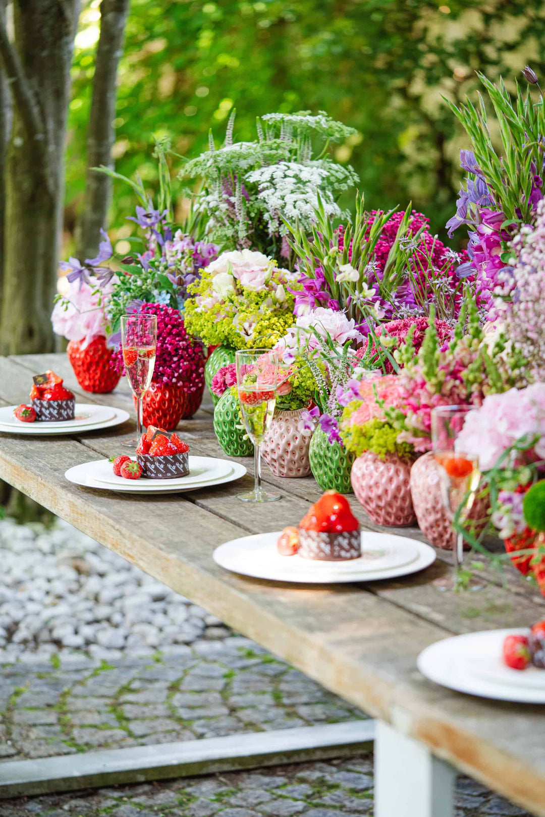 Ein sommerlich gedeckter Gartentisch mit Bahlmann Erdbeervasen und Erdbeertörtchen.