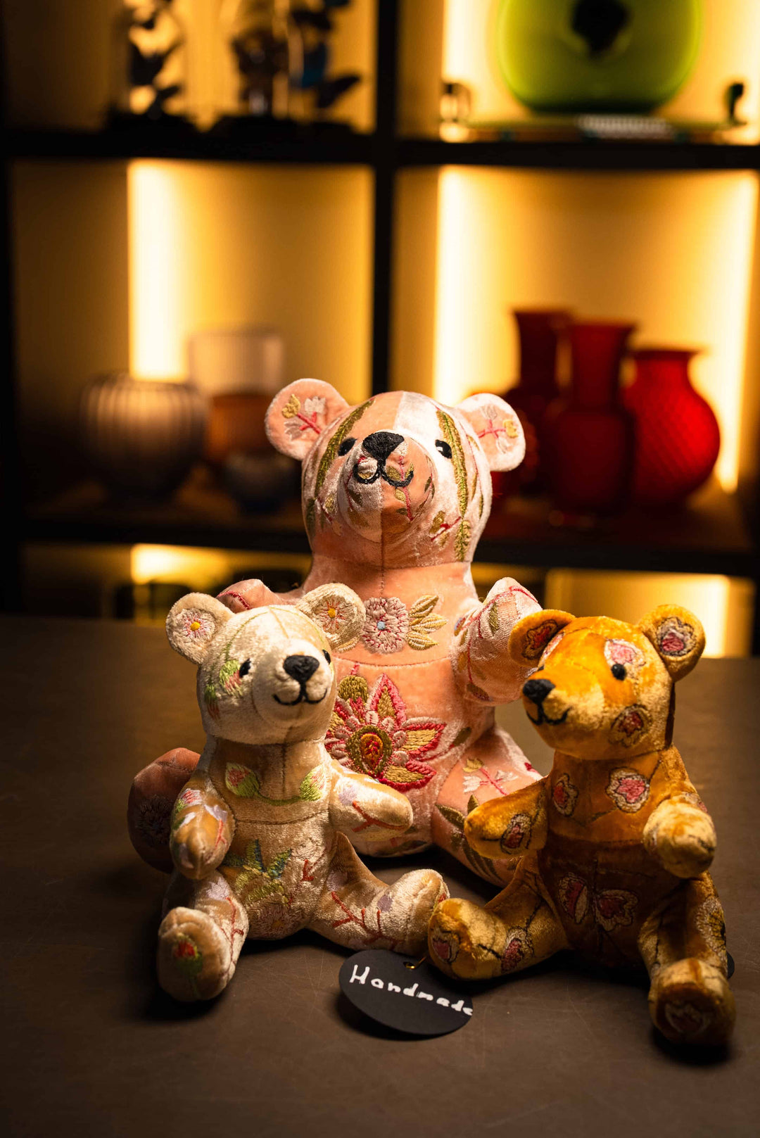 Kuscheltierbären in Beige und Goldbraun mit Mama-Bär und zwei kleine Bären, handgearbeitet und gestickt von Anke Drechsel in Deutschland. Ausgestellt vor dem Vasendisplay und zum Verkauf im Bahlmann Showroom in München. 