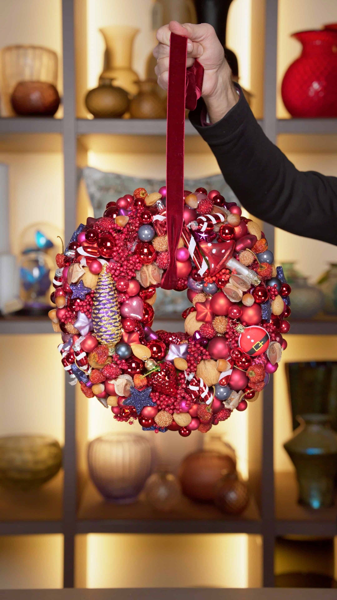 Ein weihnachtlicher Türkranz in weihnachtlichem Rot mit Ornamenten wie Zuckerstangen und Kugeln. 