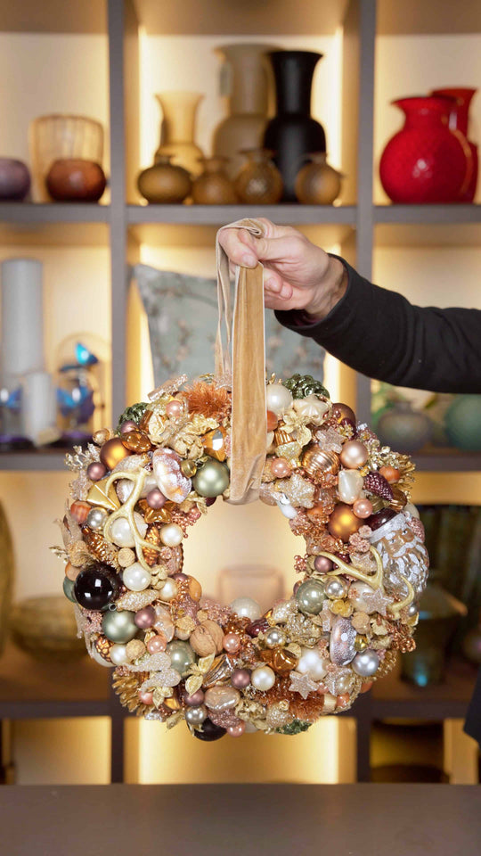 Ein Türkranz in Weiß und Gold gehalten mit einer großen Kugel in Nikolausform und Rauschebart.