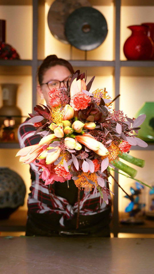 Nahaufnahme von einem Winterstrauß im SHOWROOM in München, bestehend aus Amaryllis, Nadelkissen, Eukalyptus, Orchideen, Nelken und Kapgrün.