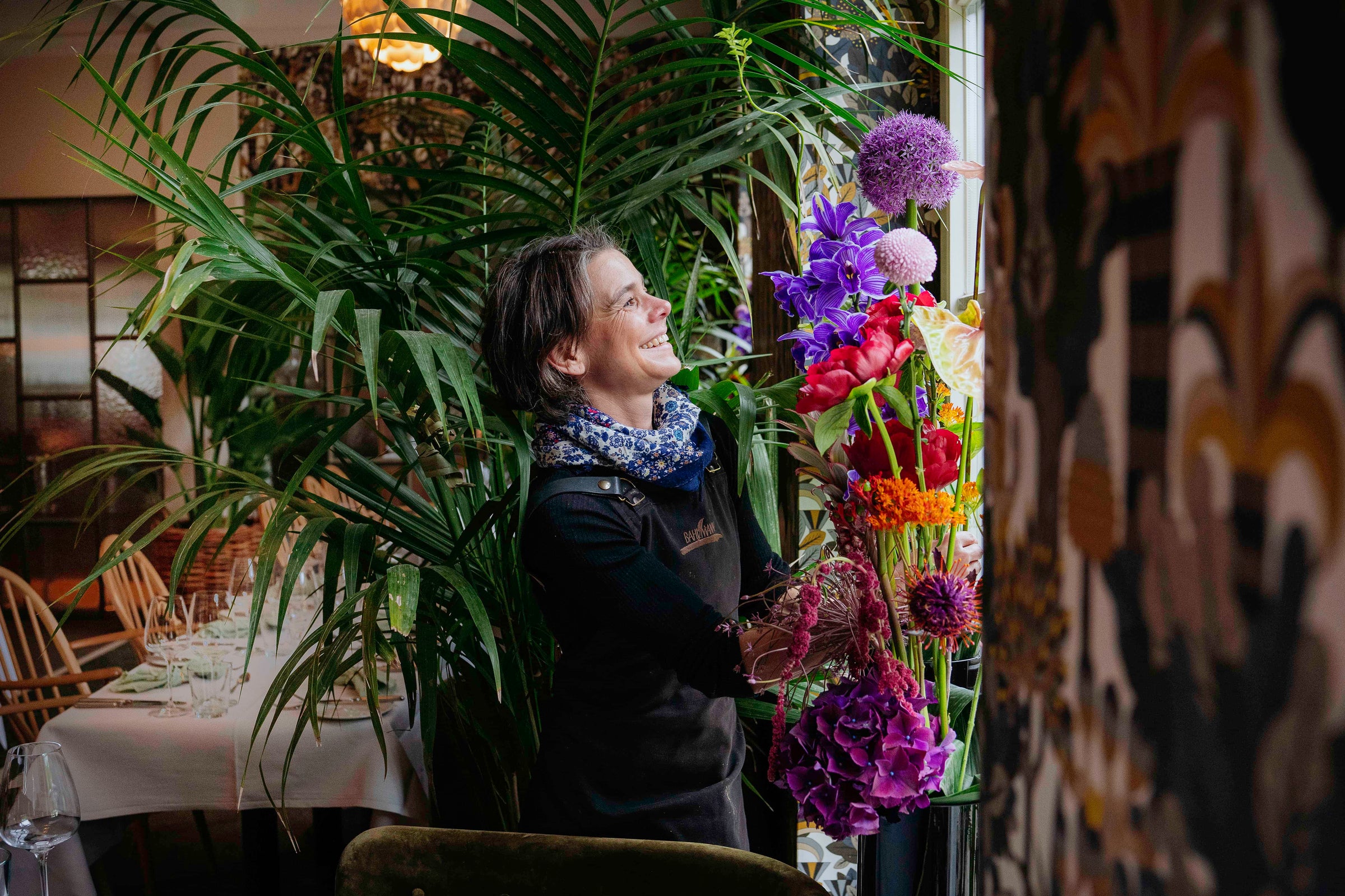 Mitarbeiterin von Blumen Bahlmann lachend und mit Freude beim Aufbau der Blumendekoration für ein Event im München.