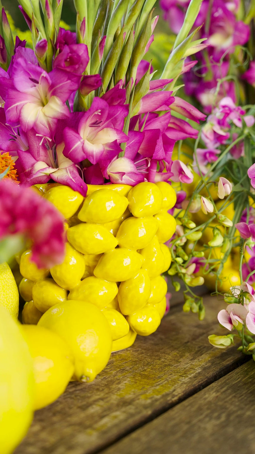 Mittelgroßer Zitronentopf, arrangiert mit Lila Blumen, von Blumen Bahlmann. Davor liegen Zitronen.