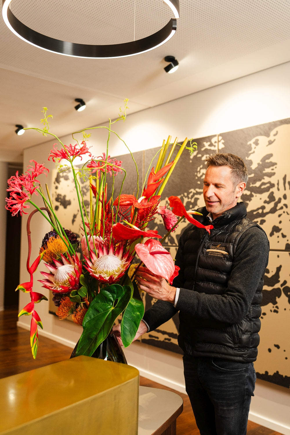 Blumen Bahlmann Geschäftsführer Michael Kötzel im Empfangsbereich mit großem Blumenarrangement bei Abonnenten eines Bahlmann Blumenabos.