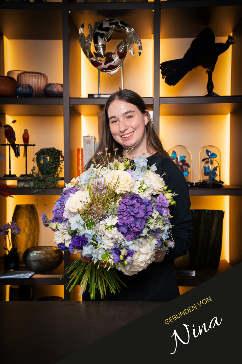 Blumenstrauß "Blütenfülle" in weiß, blau und lila Farbtönen - handgebunden und präsentiert von Bahlmann Mitarbeiterin Nina im Bahlmann Showroom in München.