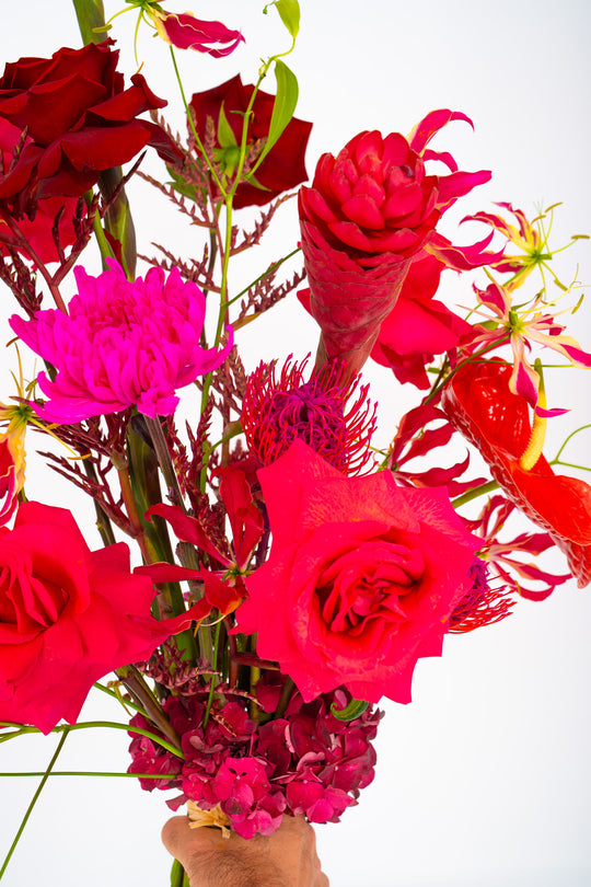 Eine POV-Ansicht des Bahlmann Blumenstrauß "Dancing Flowers" mit roten Rosen, roten Ingwerblüten und roten Anthurien.
