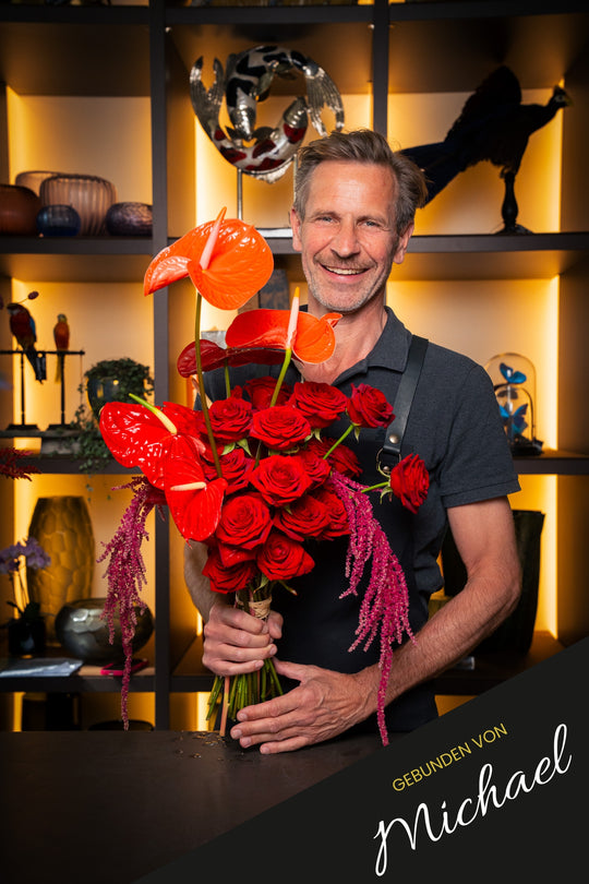 Bahlmann Geschäftsführer Michael präsentiert seinen handgebundenen Blumenstrauß "Love Cloud" mit roten Rosen und roten Anthurien im Bahlmann Showroom in München.