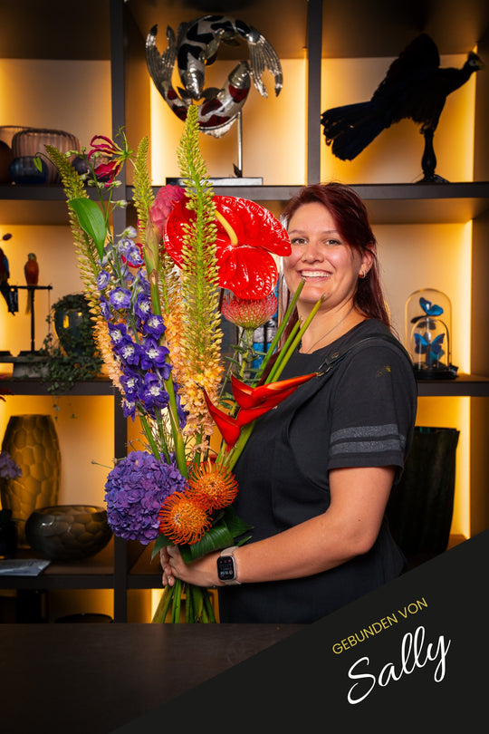 Blumenstrauß "Tropical Fire", handgebunden und präsentiert von Bahlmann Mitarbeiterin Sally – Blumen Bahlmann München