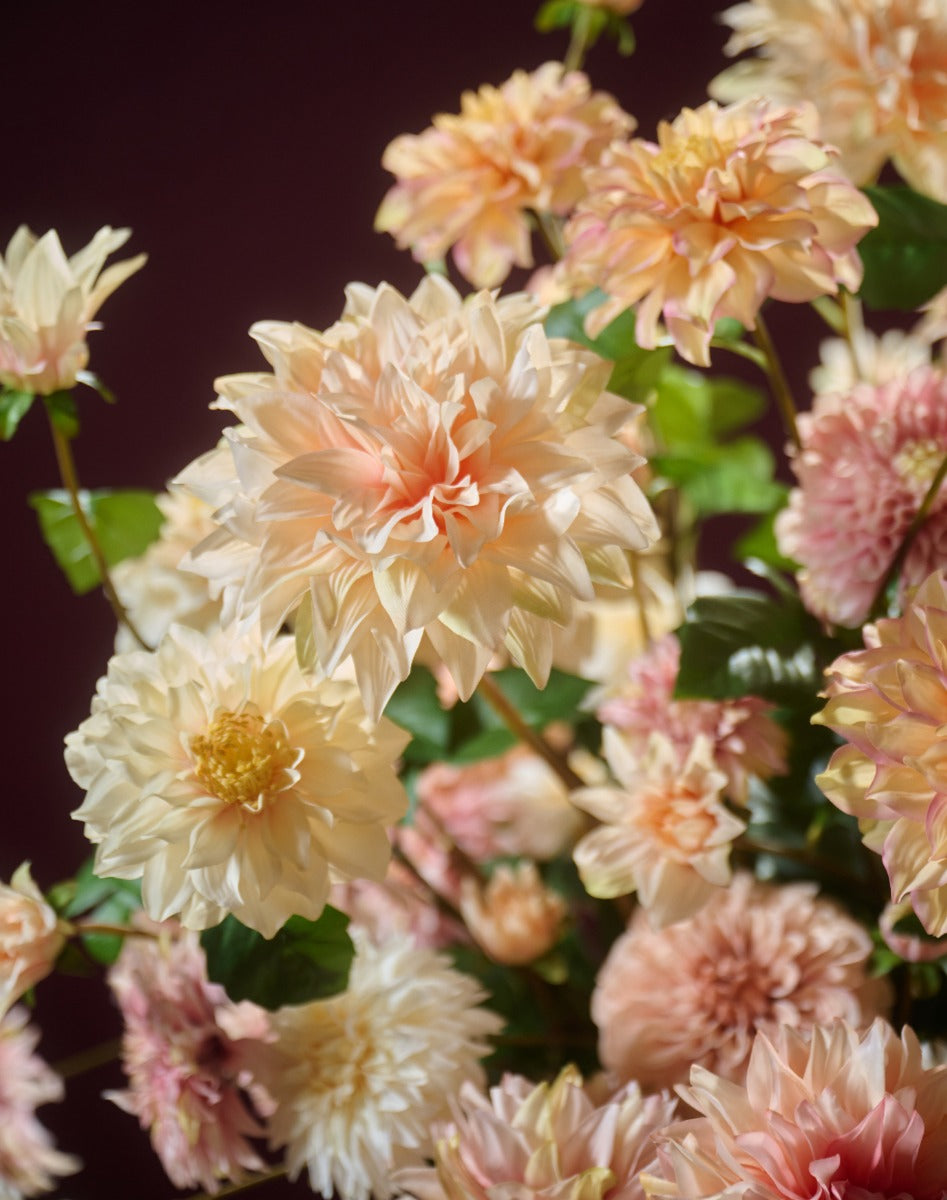 Großes künstliches Dahlienarrangement in Champagner, Creme und zartem Rosa in einer glänzenden Metallvase. Blumen Bahlmann München.