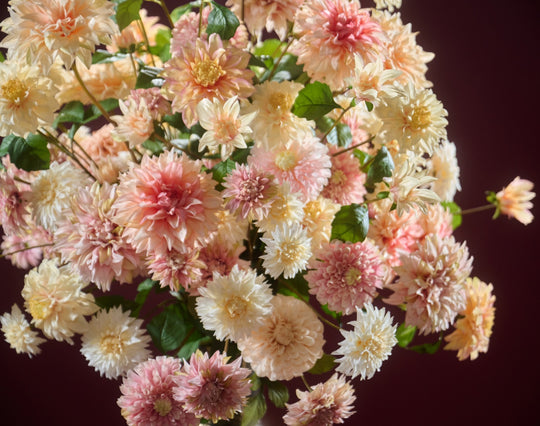 Opulentes Seidenblumengesteck mit locker angeordneten Dahlienblüten und goldener Vase. Blumen Bahlmann München.