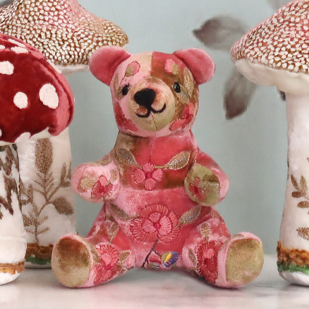 Handgestickter Teddybär in Altrosa von Anke Drechsel aus weichem Stoff mit liebevollen Details, sitzend mit freundlichem Gesichtsausdruck. Blumen Bahlmann München