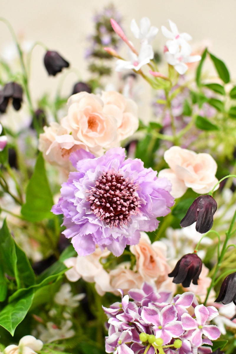 Natürlich wirkendes Kunstblumenarrangement in sanften Pastelltönen mit üppiger, lockerer Form in einer schalenförmigen Vase. Blumen Bahlmann München.