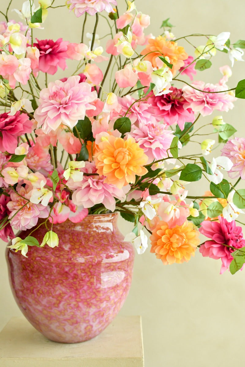 Großes künstliches Blumenarrangement mit farbenfrohen Dahlien, zarten Blüten und grünen Ranken in einer bauchigen Vase. Blumen Bahlmann München