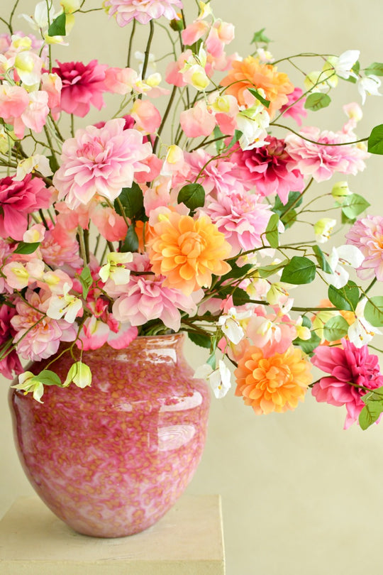 Großes künstliches Blumenarrangement mit farbenfrohen Dahlien, zarten Blüten und grünen Ranken in einer bauchigen Vase. Blumen Bahlmann München