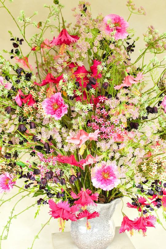 Üppiges Seidenblumenarrangement in Pink, Fuchsia, Rosé und Violett mit filigranen Zweigen in einer silberfarbenen Vase. Blumen Bahlmann München