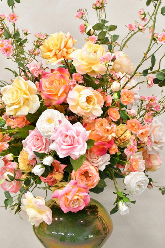 Natürlich wirkendes Seidenblumen-Gesteck mit üppigen Rosen und dekorativer Keramikvase von Blumen Bahlmann München. 