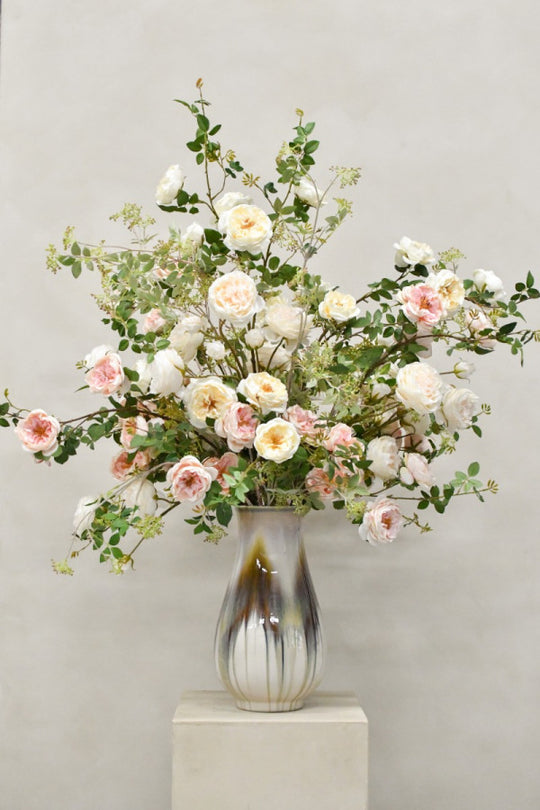 Elegantes Seidenblumenarrangement mit cremeweißen Rosen und zarten Roséblüten in dekorativer Vase von Blumen Bahmann München