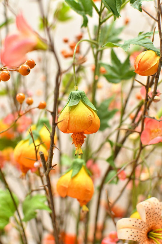 Natürlich wirkendes Seidenblumen-Gesteck mit warmen Blütenfarben und dekorativer Vase von Blumen Bahlmann München
