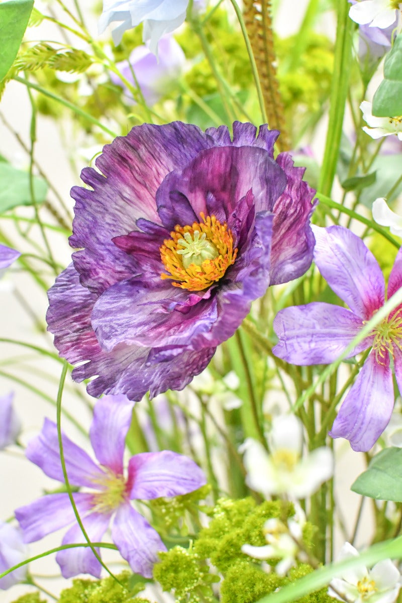 Hochwertiges künstliches Blumengesteck mit zarten Blüten, Gräsern und grünen Akzenten von Blumen Bahlmann München.