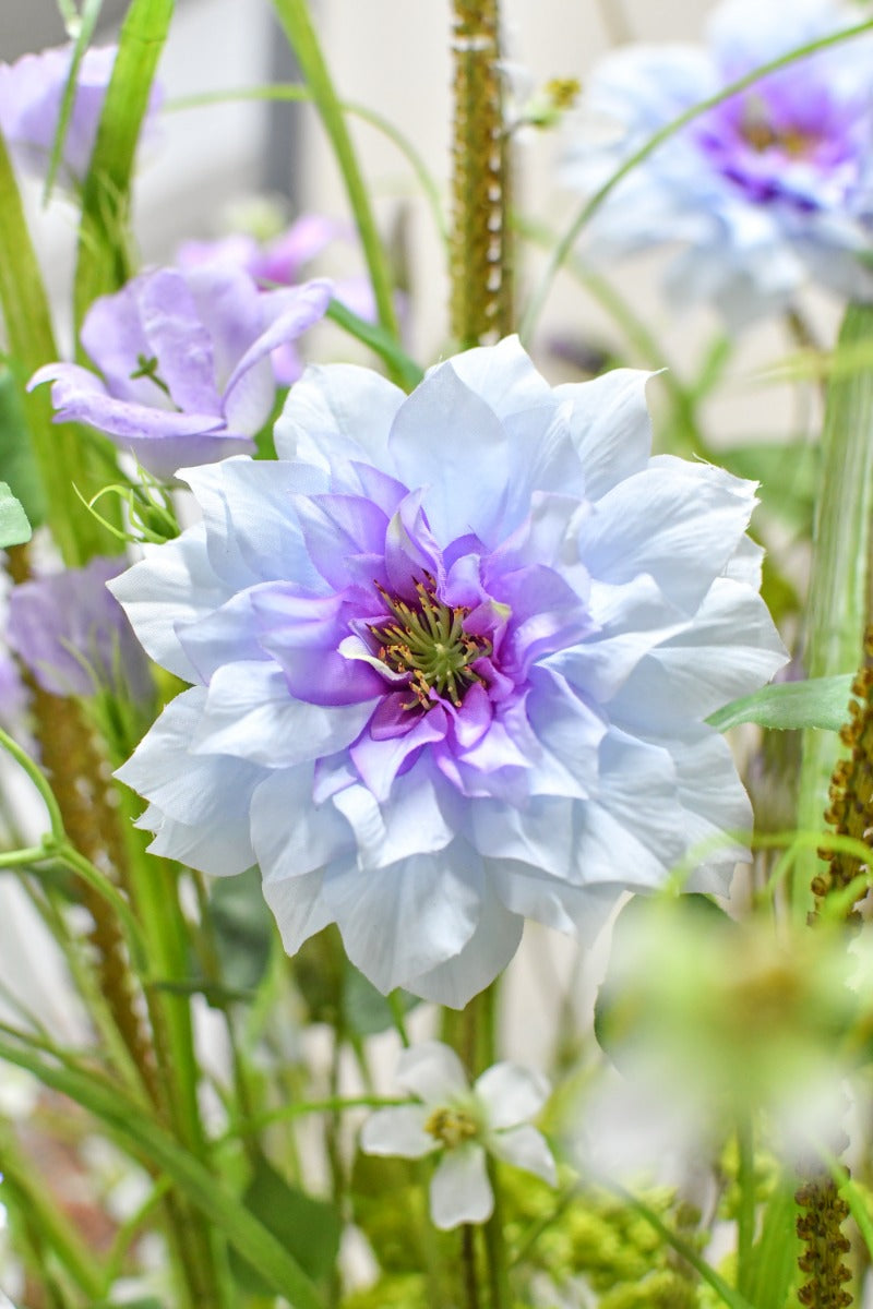 Pflegeleichtes Blumenarrangement aus künstlichen Blüten in sanften Violett- und Blautönen von Blumen Bahlmann München.