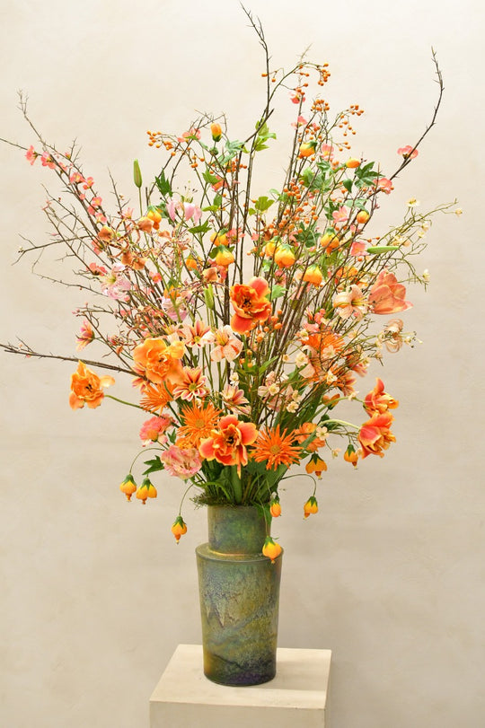 Sommerlich-herbstliches Seidenblumenarrangement in Orange, Apricot und Rosa in grünlicher Vase von Blumen Bahlmann München.